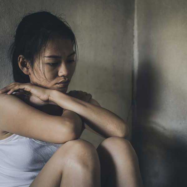 Image of a girl sitting in shadows, symbolizing trauma and survival from human trafficking.